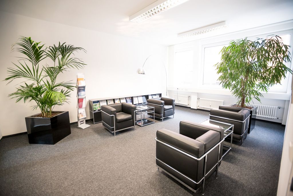 Foto des Empfangsbereichs in Stuttgart. Moderne schwarze Sitzgelegenheiten sowie grüne Pflanzen